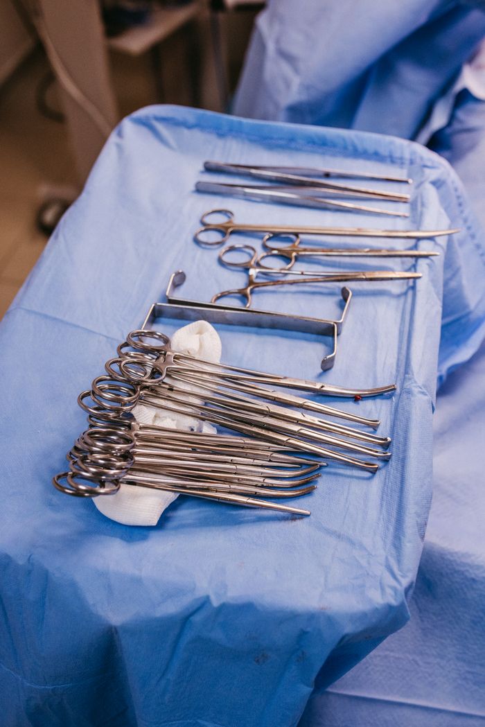 Set of sterile surgical instruments on a blue drape in an operating room.